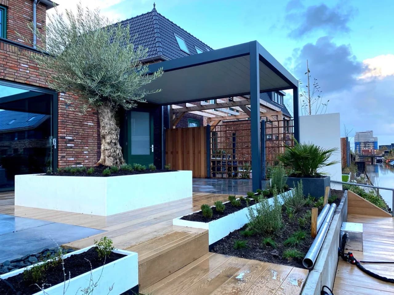 Moderne tuin met kunststof vlonders en erfafscheiding met buitenbehang in Rijswijk (Z-H)