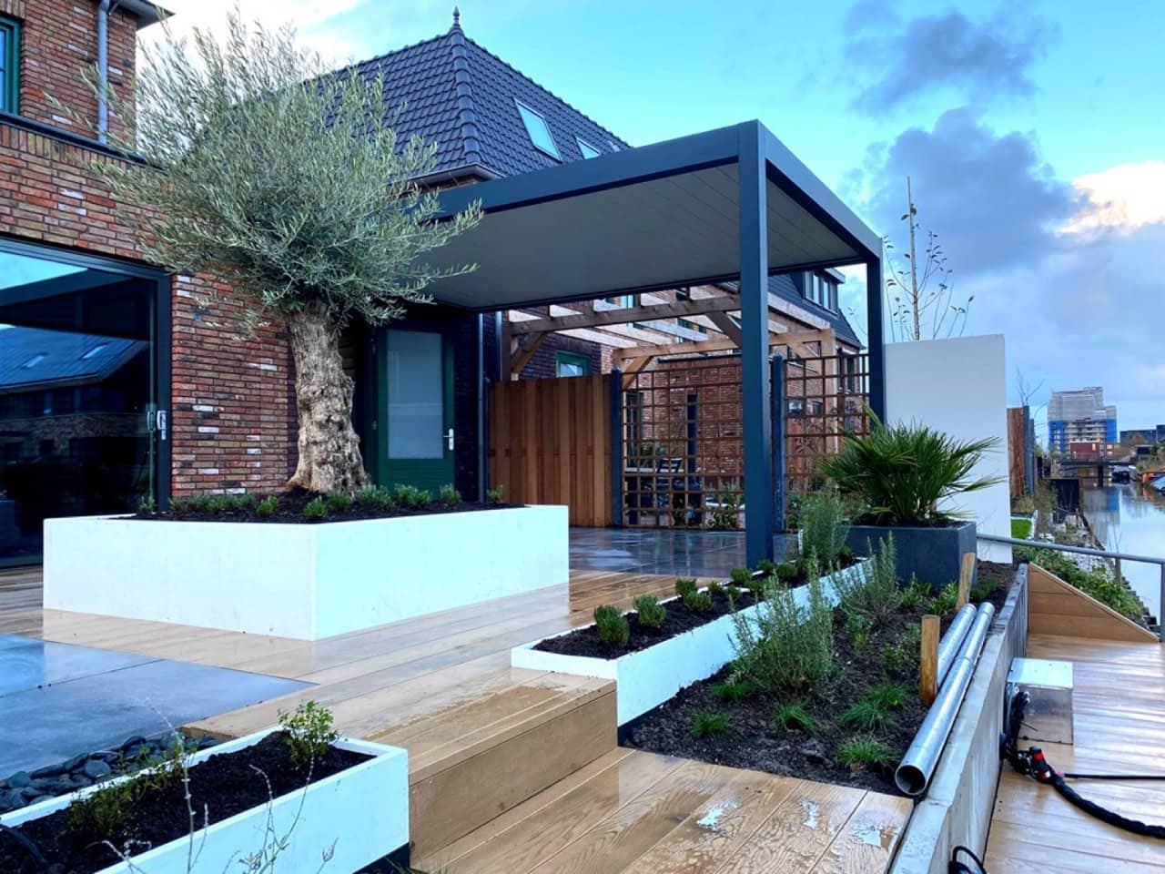 Moderne tuin met kunststof vlonders en erfafscheiding met buitenbehang in Rijswijk (Z-H)