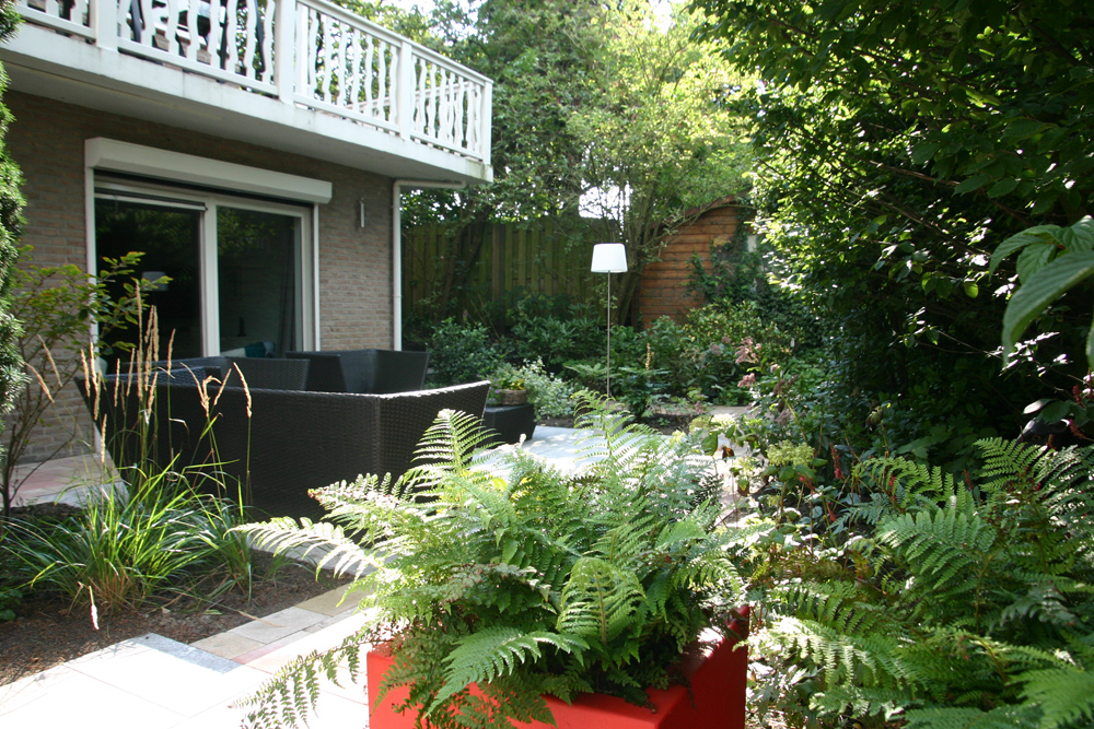 Aan de voorkant een compacte tuin langs een doorgaande weg met een greenwall geluidsscherm