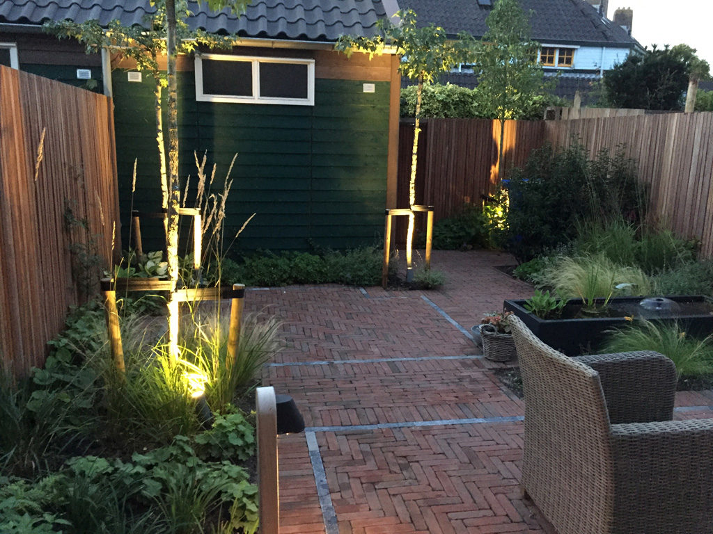 Strakke tuin in Delft met nostalgische bestrating en weelderige beplanting. Het armatuur op de voorgrond is de Beamy Teak van Royal Botania